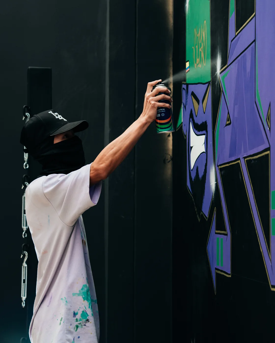 Artista pintando con aerosol el mural del gimnasio