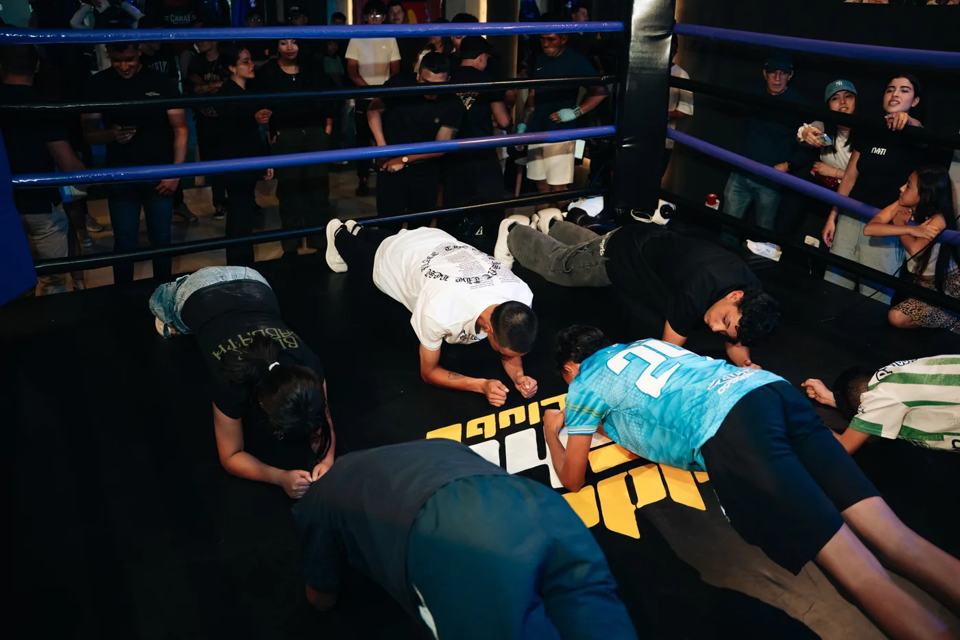 Grupo haciendo plancha dentro del ring rodeado de público